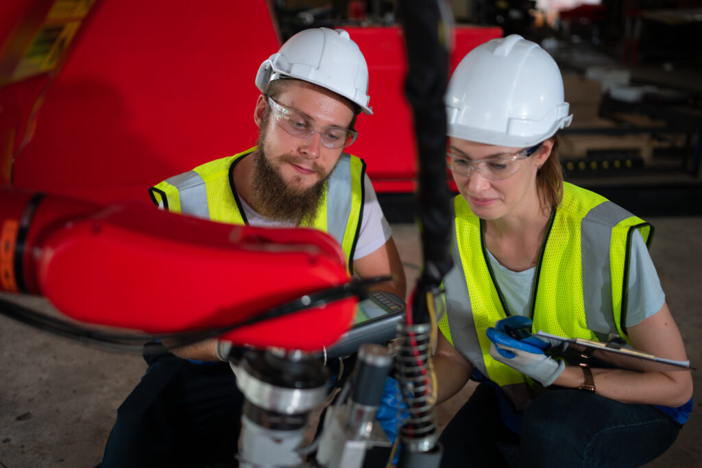 Both of engineers installing and testing a large robotic arm. be